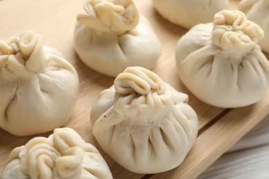 Photo of Uncooked khinkalis (dumplings) on white wooden table, closeup