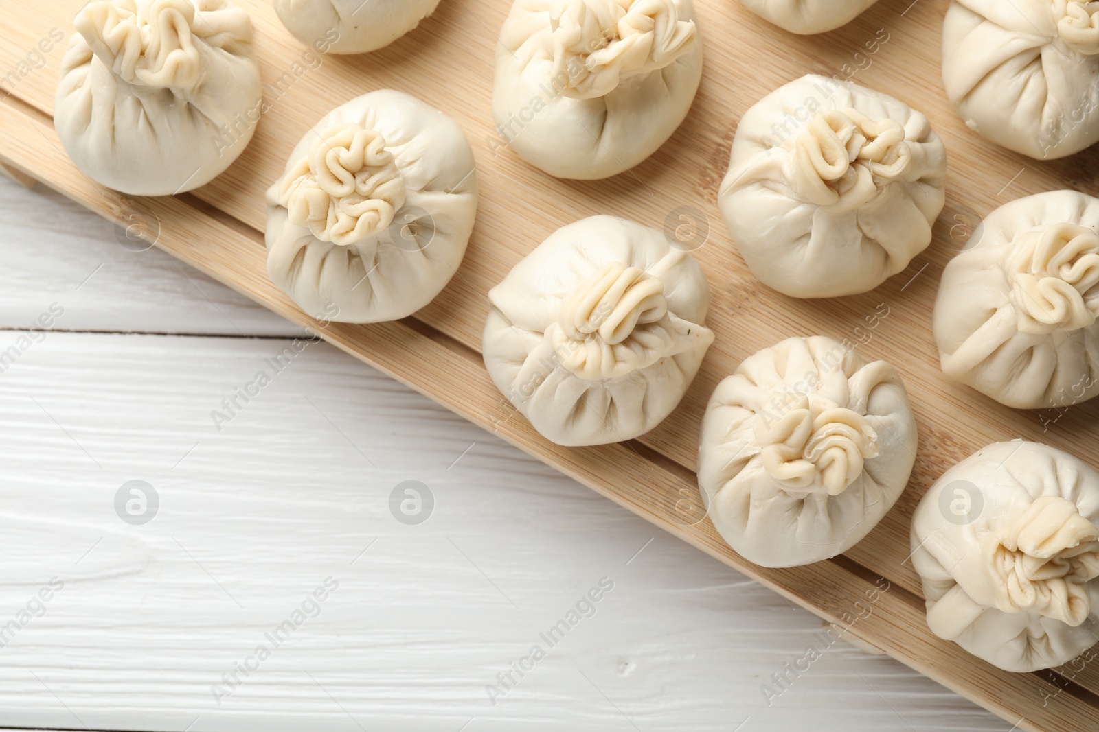 Uncooked khinkalis (dumplings) on white wooden table, top view. Space for text Photo of Uncooked khinkalis (dumplings) on white wooden table, top view. Space for text