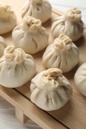 Photo of Uncooked khinkalis (dumplings) on white wooden table, closeup