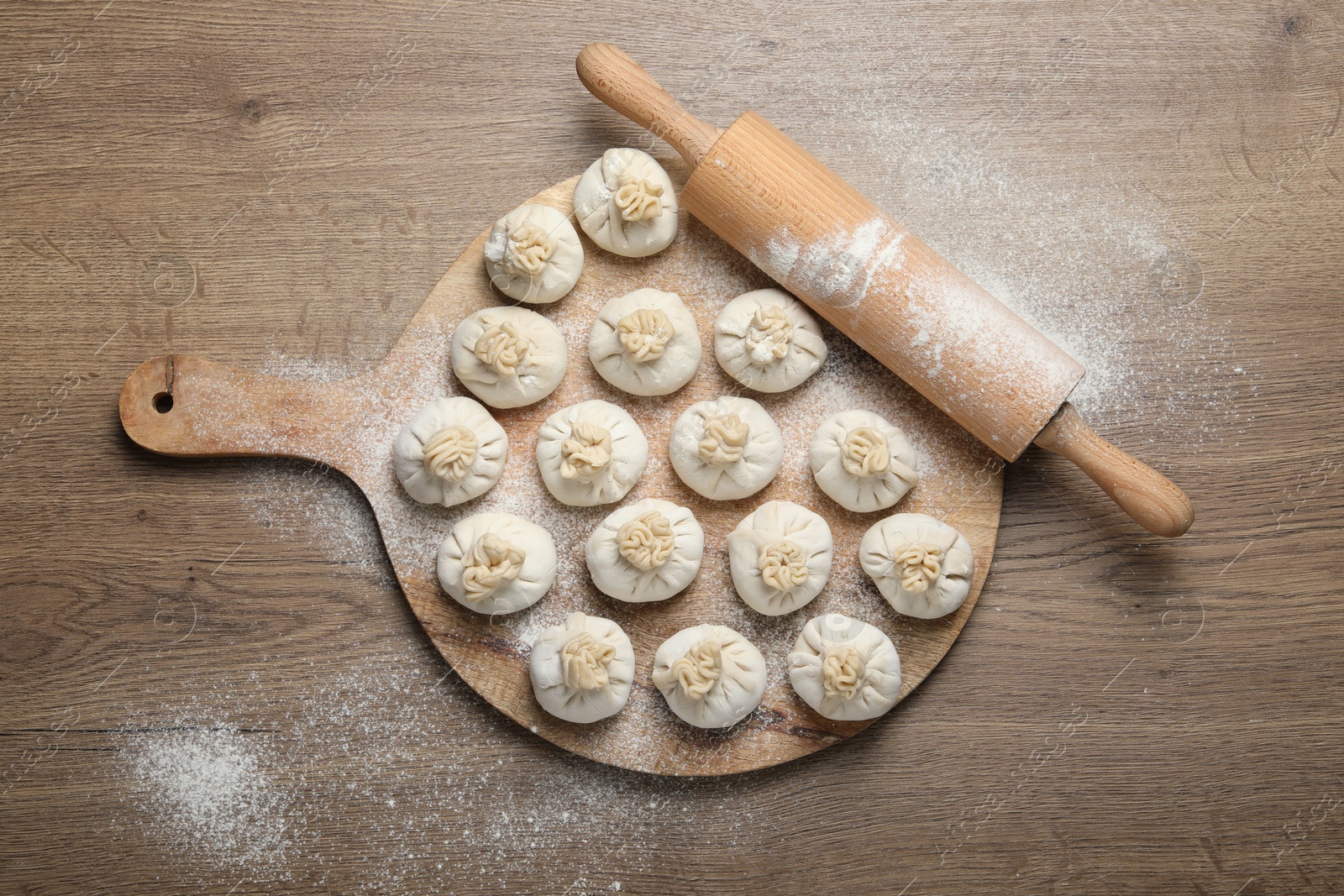Uncooked khinkalis (dumplings) and rolling pin on wooden table, top view Photo of Uncooked khinkalis (dumplings) and rolling pin on wooden table, top view