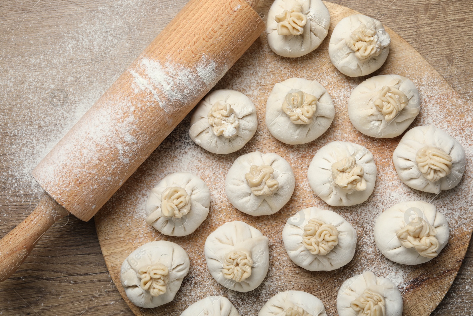 Uncooked khinkalis (dumplings) and rolling pin on wooden table, top view Photo of Uncooked khinkalis (dumplings) and rolling pin on wooden table, top view