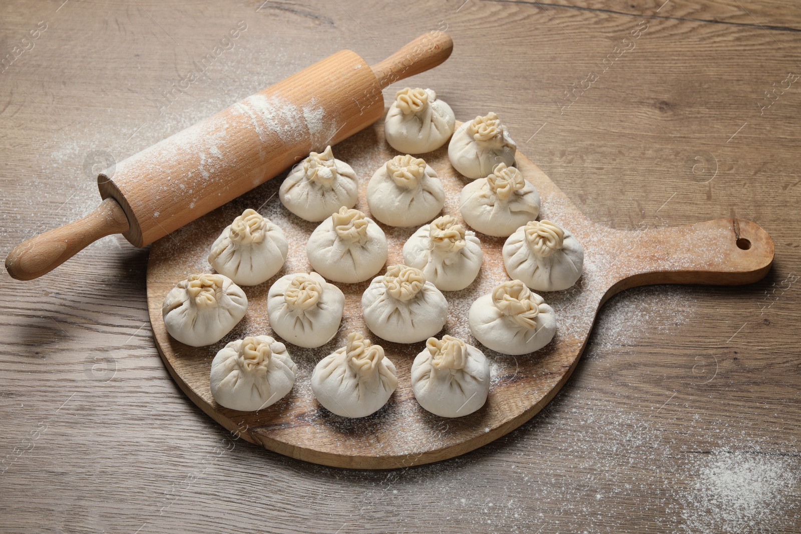 Uncooked khinkalis (dumplings) and rolling pin on wooden table, above view Photo of Uncooked khinkalis (dumplings) and rolling pin on wooden table, above view