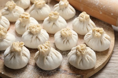 Photo of Uncooked khinkalis (dumplings) and rolling pin on wooden table, closeup