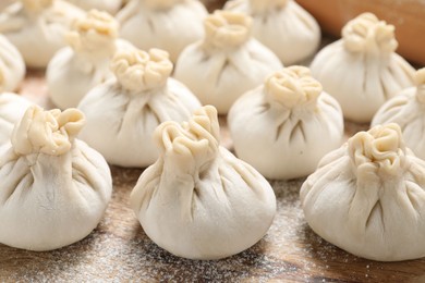 Photo of Uncooked khinkalis (dumplings) on wooden table, closeup