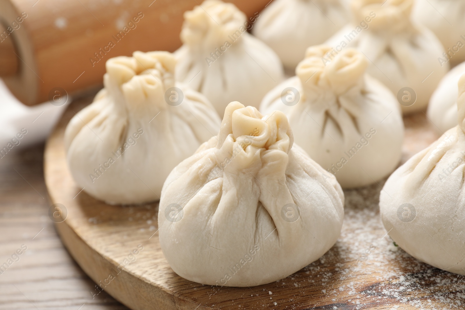 Uncooked khinkalis (dumplings) and rolling pin on wooden table, closeup Photo of Uncooked khinkalis (dumplings) and rolling pin on wooden table, closeup