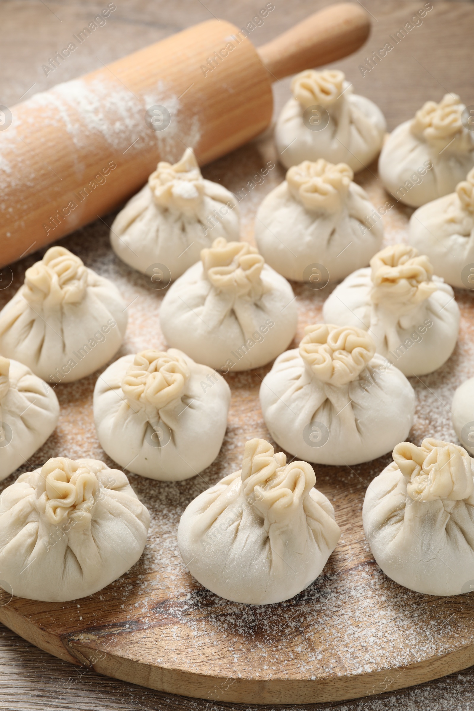 Uncooked khinkalis (dumplings) and rolling pin on table, closeup Photo of Uncooked khinkalis (dumplings) and rolling pin on table, closeup