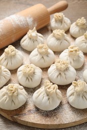 Photo of Uncooked khinkalis (dumplings) and rolling pin on table, closeup