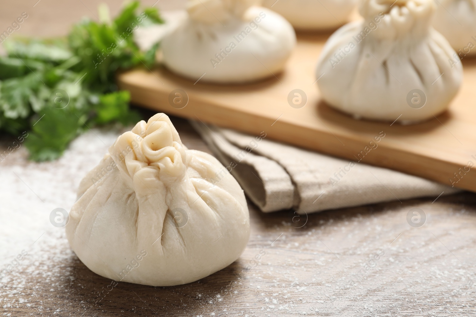 Uncooked khinkalis (dumplings) and cilantro on wooden table, closeup Photo of Uncooked khinkalis (dumplings) and cilantro on wooden table, closeup
