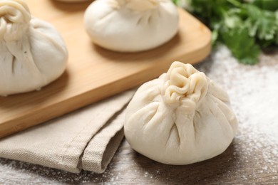 Photo of Uncooked khinkalis (dumplings) and cilantro on wooden table, closeup
