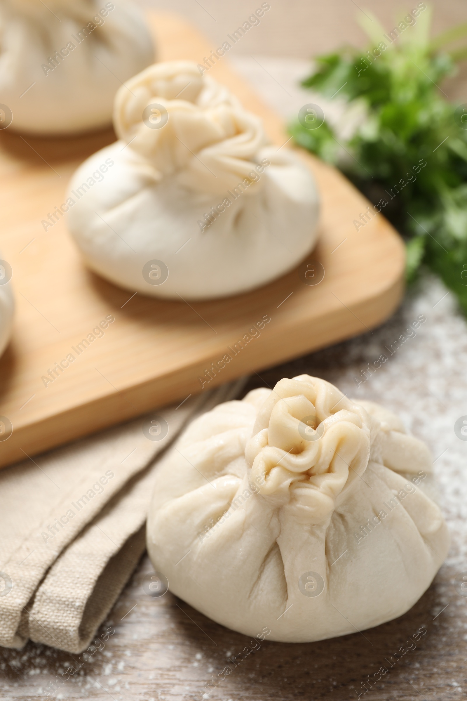 Uncooked khinkalis (dumplings) and cilantro on wooden table, closeup Photo of Uncooked khinkalis (dumplings) and cilantro on wooden table, closeup