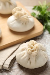 Photo of Uncooked khinkalis (dumplings) and cilantro on wooden table, closeup