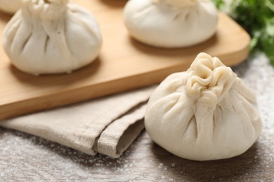 Photo of Uncooked khinkalis (dumplings) and cilantro on wooden table, closeup