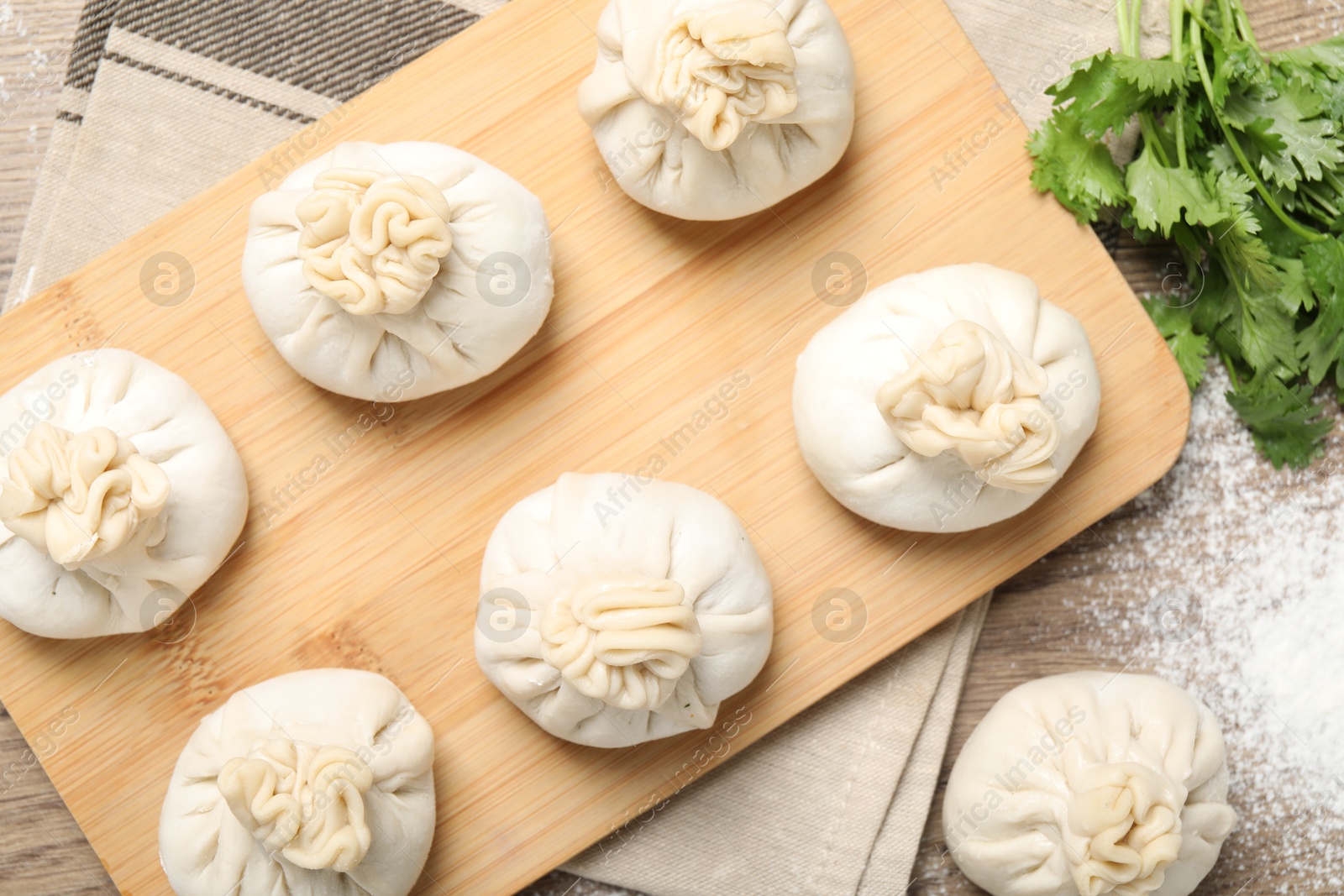 Uncooked khinkalis (dumplings) and cilantro on wooden table, flat lay Photo of Uncooked khinkalis (dumplings) and cilantro on wooden table, flat lay