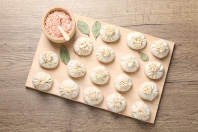 Photo of Uncooked khinkalis (dumplings) and spices on wooden table, top view