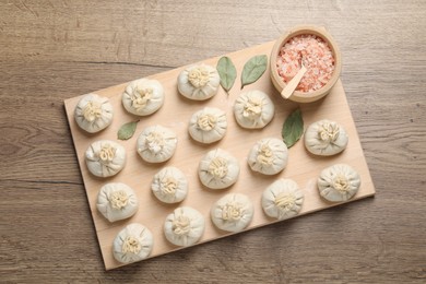 Photo of Uncooked khinkalis (dumplings) and spices on wooden table, top view