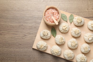 Photo of Uncooked khinkalis (dumplings) and spices on wooden table, top view. Space for text