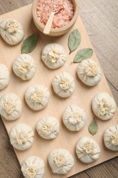 Photo of Uncooked khinkalis (dumplings) and spices on wooden table, top view