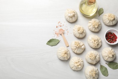 Photo of Uncooked khinkalis (dumplings) and spices on white wooden table, flat lay. Space for text