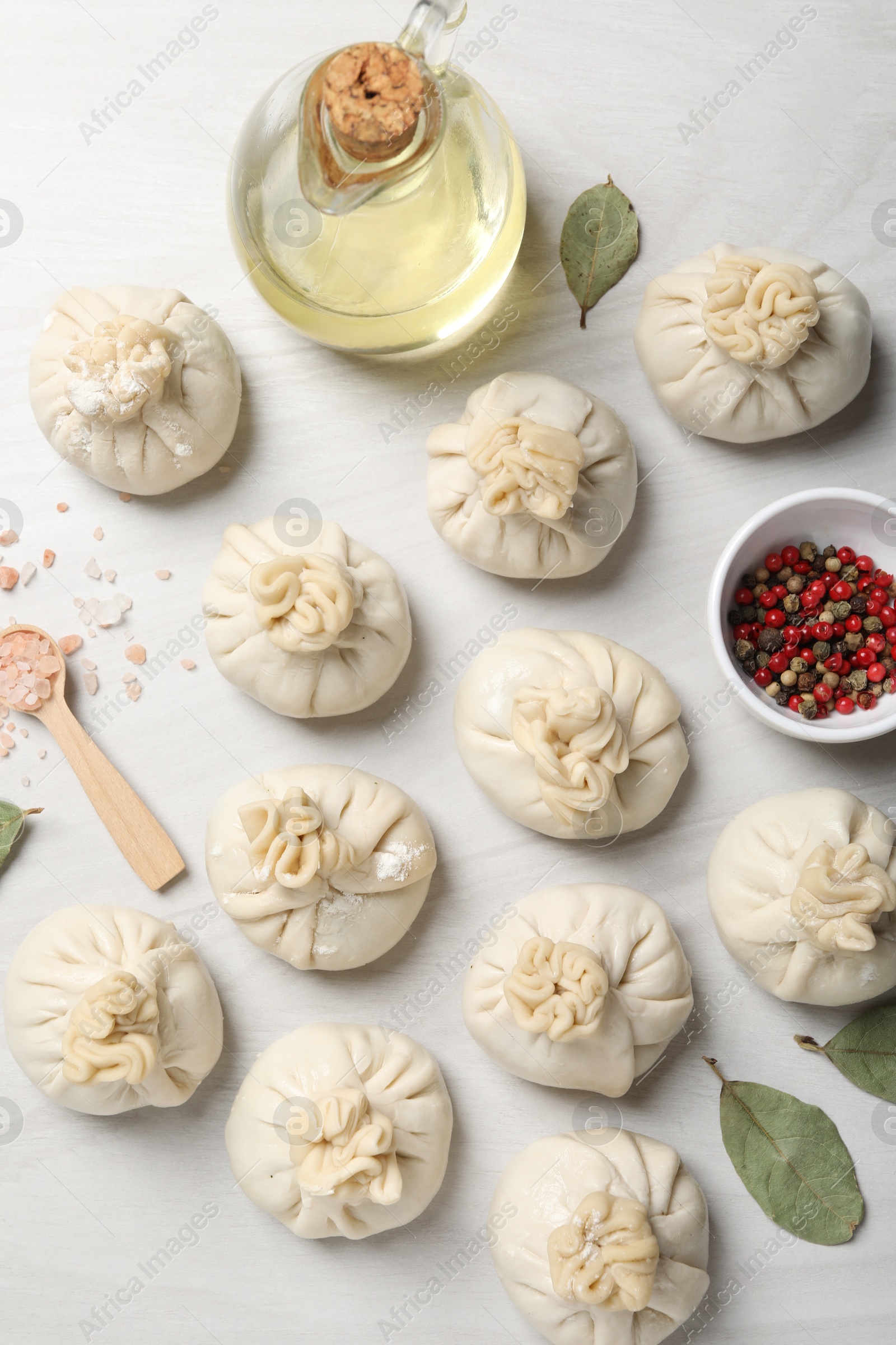 Photo of Uncooked khinkalis (dumplings) and spices on white wooden table, flat lay