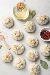Photo of Uncooked khinkalis (dumplings) and spices on white wooden table, flat lay