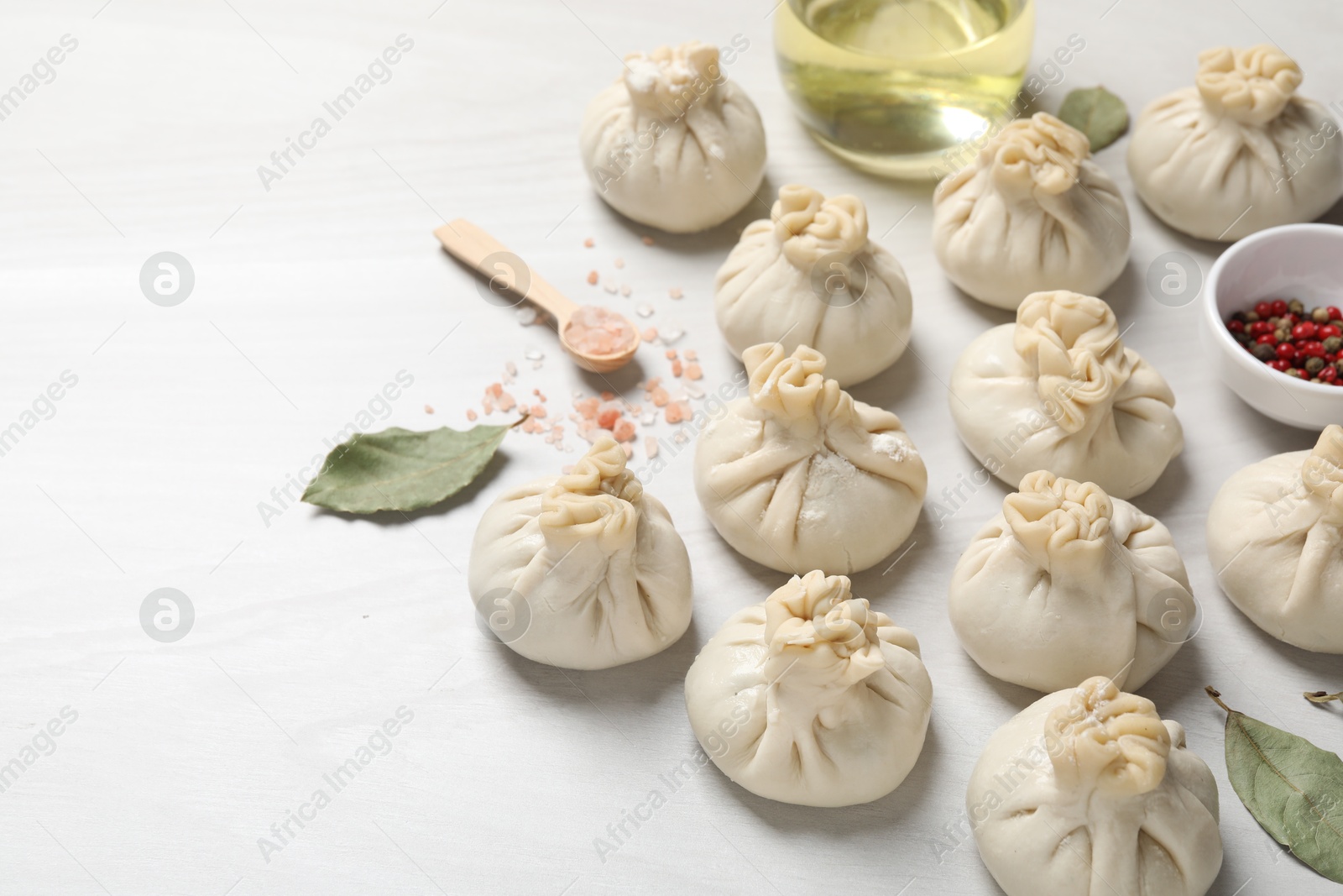 Photo of Uncooked khinkalis (dumplings) and spices on white wooden table, closeup. Space for text