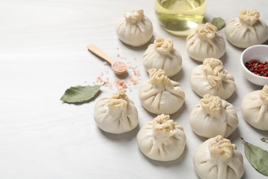 Photo of Uncooked khinkalis (dumplings) and spices on white wooden table, closeup. Space for text