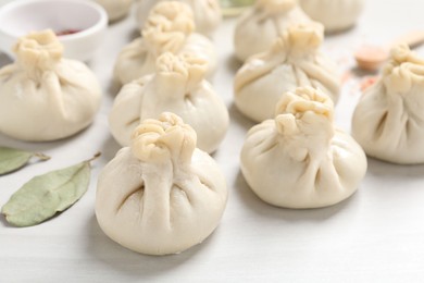 Photo of Uncooked khinkalis (dumplings) and spices on white wooden table, closeup