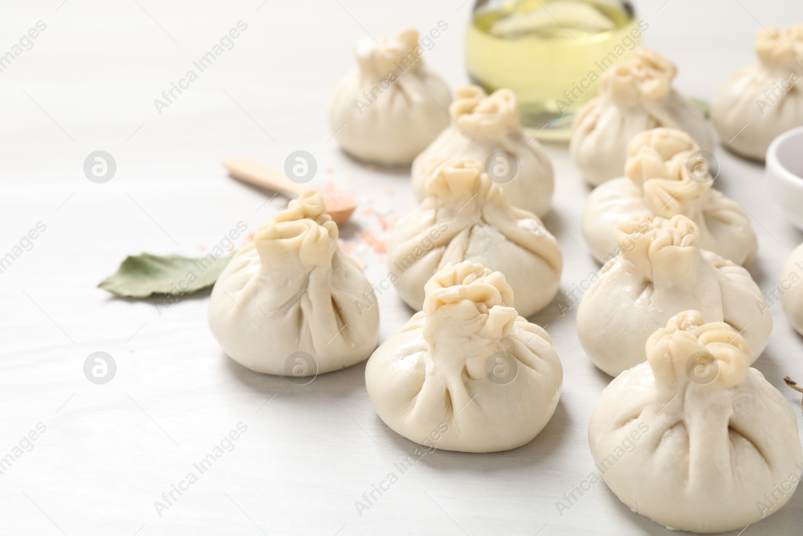 Uncooked khinkalis (dumplings) and spices on white wooden table, closeup Photo of Uncooked khinkalis (dumplings) and spices on white wooden table, closeup