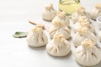 Photo of Uncooked khinkalis (dumplings) and spices on white wooden table, closeup
