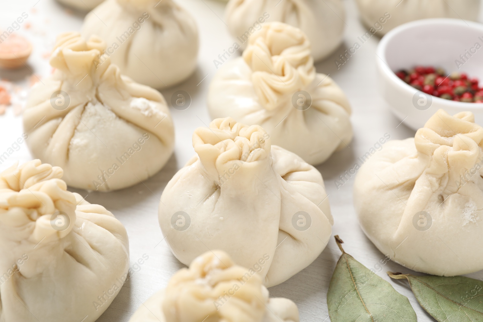 Uncooked khinkalis (dumplings) and spices on white wooden table, closeup Photo of Uncooked khinkalis (dumplings) and spices on white wooden table, closeup