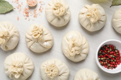 Photo of Uncooked khinkalis (dumplings) and spices on white wooden table, flat lay