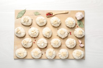 Photo of Uncooked khinkalis (dumplings) and spices on white wooden table, top view