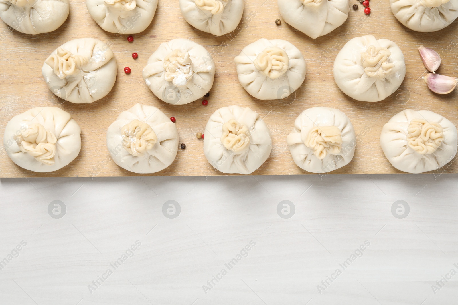 Uncooked khinkalis (dumplings) and spices on white wooden table, top view. Space for text Photo of Uncooked khinkalis (dumplings) and spices on white wooden table, top view. Space for text