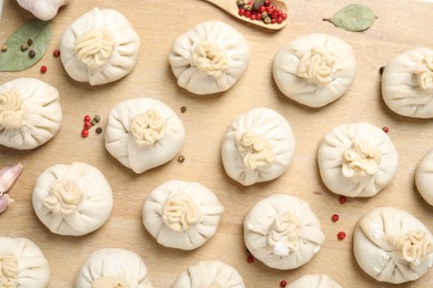 Photo of Uncooked khinkalis (dumplings) and spices on wooden table, flat lay