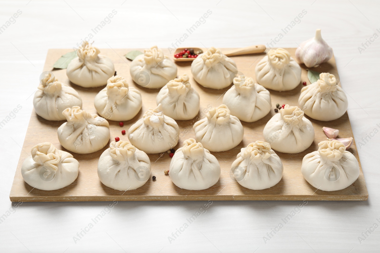 Uncooked khinkalis (dumplings) and spices on white wooden table, closeup Photo of Uncooked khinkalis (dumplings) and spices on white wooden table, closeup