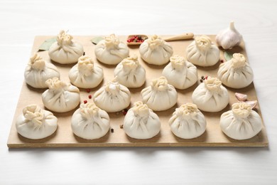 Photo of Uncooked khinkalis (dumplings) and spices on white wooden table, closeup