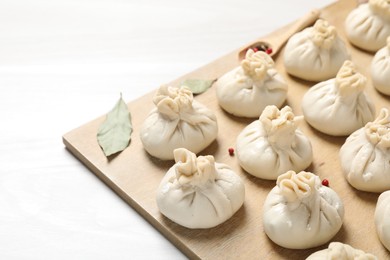 Photo of Uncooked khinkalis (dumplings) and spices on white wooden table, closeup