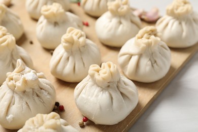 Photo of Uncooked khinkalis (dumplings) and spices on white table, closeup