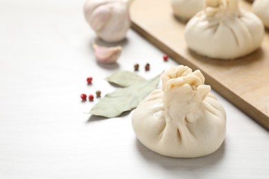 Photo of Uncooked khinkalis (dumplings) and spices on white wooden table, closeup. Space for text