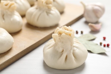 Photo of Uncooked khinkalis (dumplings) and spices on white wooden table, closeup
