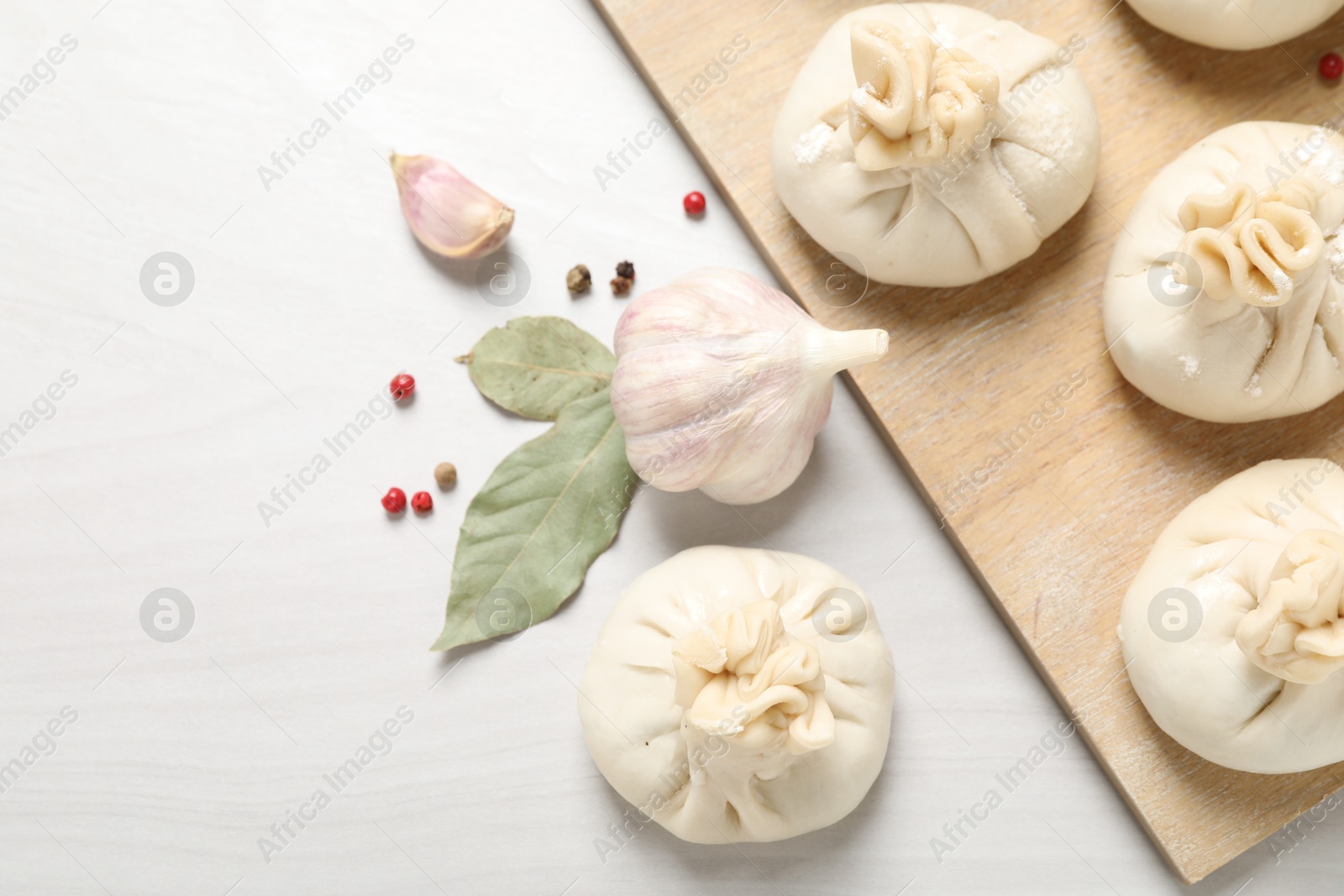 Uncooked khinkalis (dumplings) and spices on white wooden table, flat lay. Space for text Photo of Uncooked khinkalis (dumplings) and spices on white wooden table, flat lay. Space for text