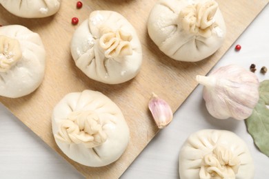 Photo of Uncooked khinkalis (dumplings) and spices on white wooden table, flat lay