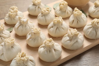 Photo of Uncooked khinkalis (dumplings) on wooden table, closeup