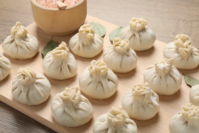 Photo of Uncooked khinkalis (dumplings) and spices on wooden table, closeup
