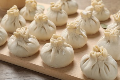 Photo of Uncooked khinkalis (dumplings) on wooden table, closeup