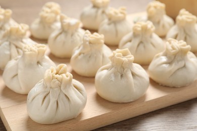 Photo of Uncooked khinkalis (dumplings) on wooden table, closeup