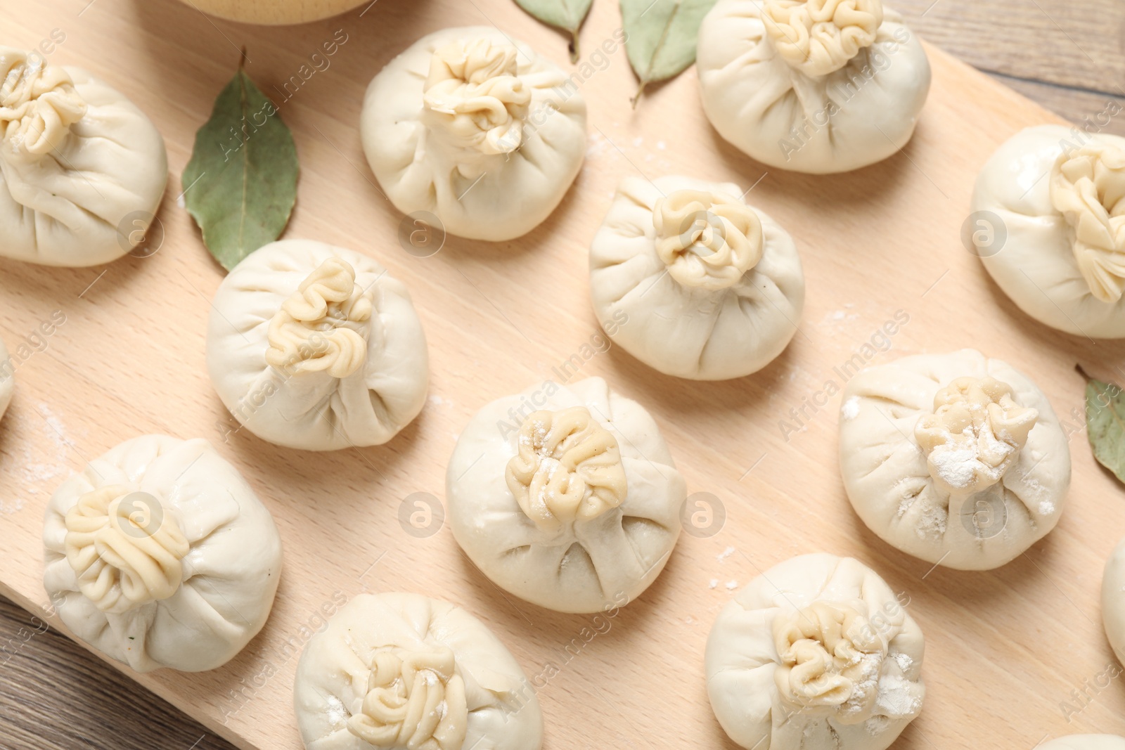 Photo of Uncooked khinkalis (dumplings) and spices on wooden table, top view
