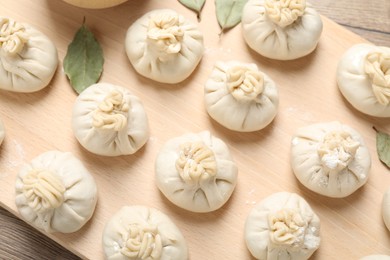 Photo of Uncooked khinkalis (dumplings) and spices on wooden table, top view