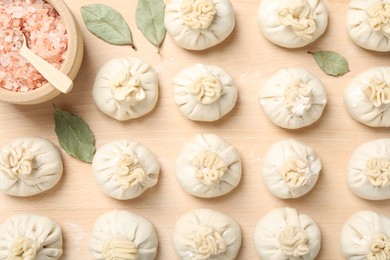 Photo of Uncooked khinkalis (dumplings) and spices on wooden table, flat lay