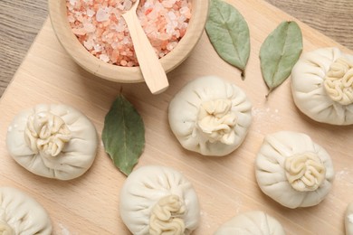Photo of Uncooked khinkalis (dumplings) and spices on wooden table, top view